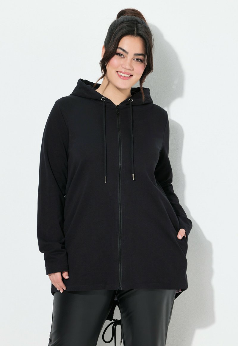 Sudadera negra con cremallera, capucha, mangas largas y dos bolsillos laterales; hecha de tela suave, con detalles de cordones.