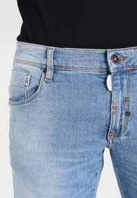 Ljusblå denimjeans med rak benform, knappgylf med metallknapp och klassisk femficksdesign.