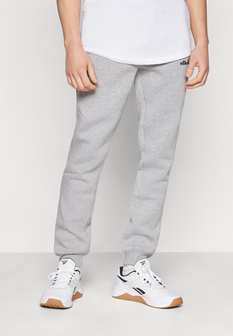 Grå joggebukser laget av myk stoff, med en innsnittet passform, elastiske mansjetter, og en liten svart logo på midjebåndet.