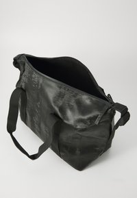 Black shoulder bag made of textured material, featuring two fabric handles and a zip closure. Spacious interior with a minimalist design.