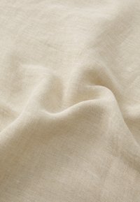 Naturlig linnedstof, lys beige farve, tekstureret vævning, med blød drapering og subtil glans. Glat overflade med en let ujævn finish.
