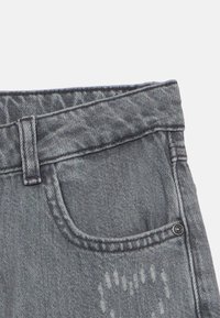 Γκρι τζιν παντελόνι από τζιν ύφασμα με κλασικό σχέδιο πέντε τσεπών. Διαθέτει κούμπωμα με κουμπί και διακοσμητικές ραφές γύρω από τη μέση και τις τσέπες.