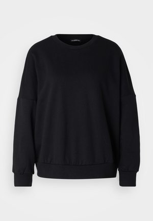 Melna džemperis ar apaļu kaklu, brīvu piegriezumu, pazeminātām plecu līnijām, ribota aproce un strukturēta auduma. Minimālistisks dizains bez rakstiem.