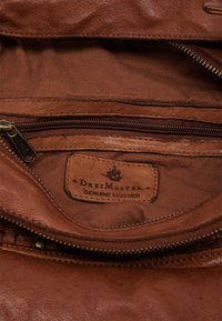 Bruin lederen interieur met een zakje met rits. Opvallend label met de tekst "DreiMaster Echt Leder." Gladde textuur met subtiele glans.