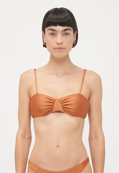 Ruskea bikinitoppi ohuilla olkaimilla, jossa on kiertynyt etuosasuunnittelu. Valmistettu sileästä kankaasta, se omaa yhtenäisen värin ja minimalistisen tyylin.