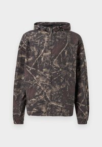 Giacca con cappuccio nera con un motivo in tan invecchiato. Presenta polsini elasticizzati, una zip a lunghezza totale e un tessuto leggero.