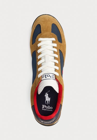Smeđi suedes i mornarski tekstilni tenisice s bijelim vezicama, crvenim unutarnjim oblogama i velikim Polo logotipom na jeziku. Crni potplat.