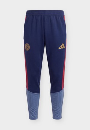 Granatowe spodnie sportowe z czerwonymi paskami po bokach, jasnoniebieskimi dolnymi partiami nóg, herbem Bayernu Monachium na lewej udzie oraz złotym logo Adidas na prawym udzie.