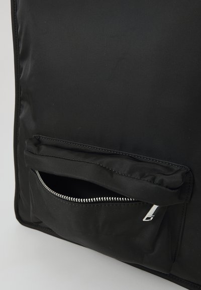 Black backpack made of durable fabric with a zippered front pocket and silver hardware. Slight texture on the material, rectangular shape.
