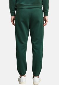 Donkergroene joggers van zacht materiaal, met elastische boorden bij de enkels en een relaxte pasvorm. De tailleband is ook rekbaar voor extra comfort.