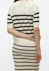 Pletený svetr s krátkými rukávy; krémový základ s černými vodorovnými pruhy; přiléhavý střih, žebrovaná textura a kontrastní lem.