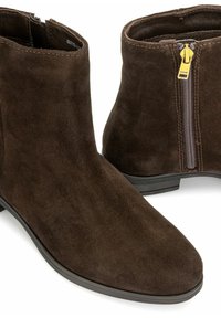 Brązowe zamszowe botki za kostkę z zaokrąglonym noskiem, zamkiem błyskawicznym z boku ozdobionym żółtym metalem oraz niskim czarnym obcasem dla lepszej stabilności.