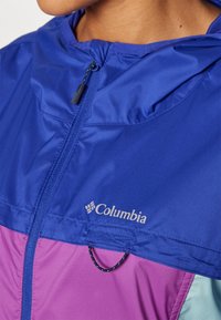 Colorful Columbia jacket featuring blue fabric at the top, transitioning to pink, with a functional zipper and logo detail.