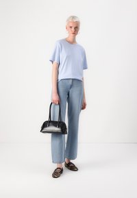 Light blue short-sleeve t-shirt, blue high-waisted jeans, black leather handbag with rounded handles, and leopard-print loafers.