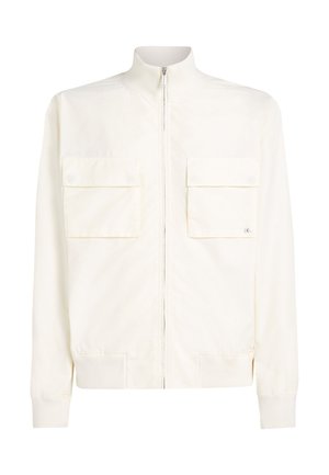 Blouson aviateur crème clair en tissu lisse, doté d'un col montant, d'une fermeture éclair frontale et de deux poches poitrine à rabat. Poignets côtelés.