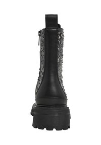 Stivaletti neri in pelle con borchie decorative, dotati di suola in gomma spessa e chiusura con zip. La vista posteriore mette in evidenza i dettagli texture.