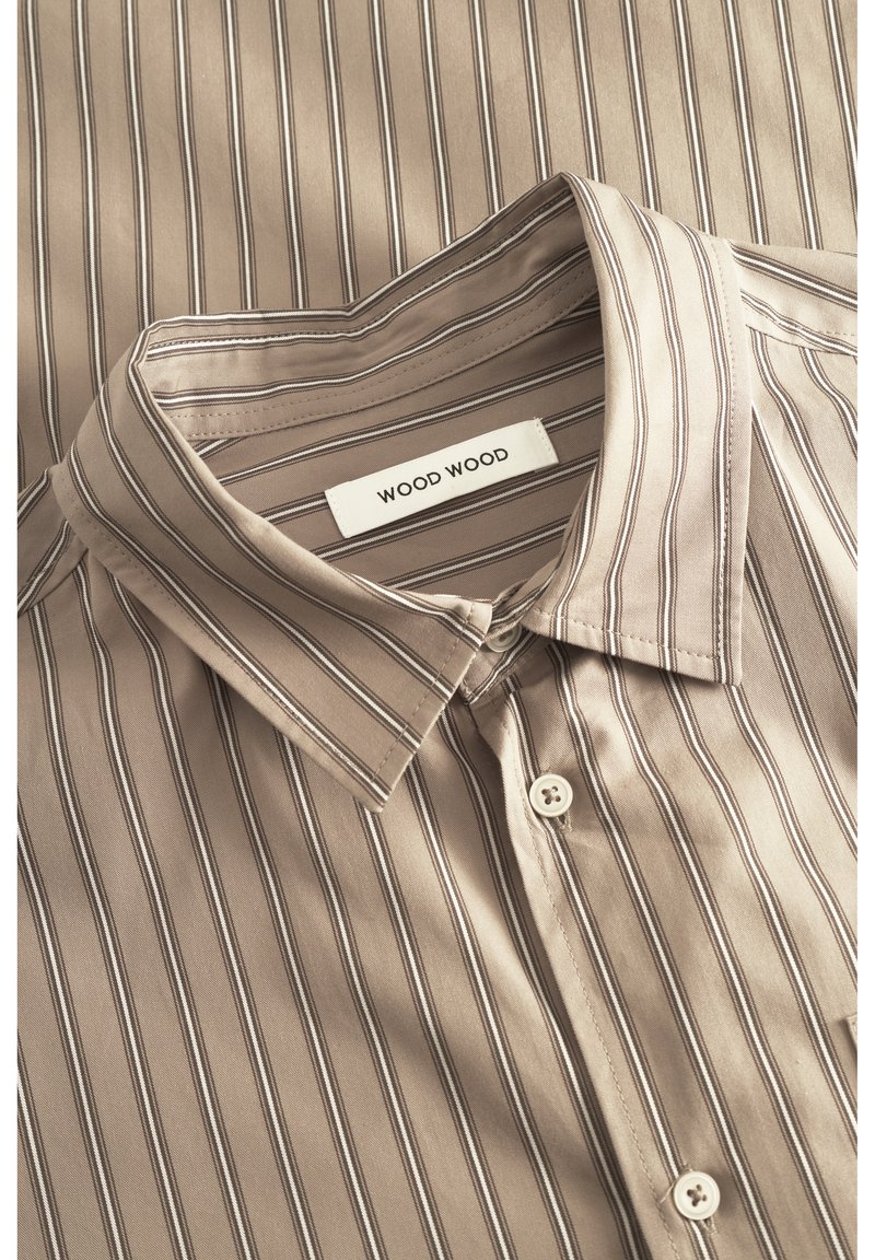 Camicia a righe beige con colletto a punta, realizzata in tessuto liscio. Presenta linee verticali in tonalità più scure e una piccola etichetta bianca con la scritta "WOOD WOOD".