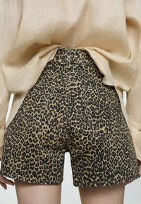 Shorts in denim con stampa leopardata con vita alta, dotati di cinque tasche, cuciture a contrasto e una texture del tessuto resistente.