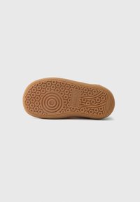 Såle av en brun Puma-sneaker med sirkulære spor mønstre, Puma-logo, og teksten "ikke merkende" på en hvit bakgrunn.