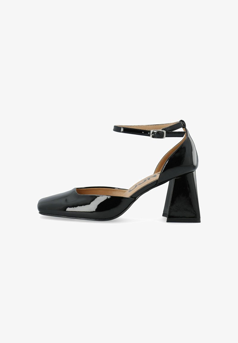 Pump en cuir verni noir avec un bout carré et un talon bloc épais. Présente une sangle à la cheville avec une boucle en argent et une doublure intérieure lisse.