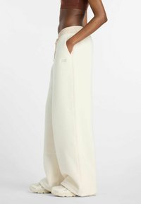 Wijdvallende crème sweatpants van zachte stof met een elastische tailleband en trekkoord. Voorzien van zijzakken en subtiele logodetails.