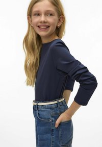 Granatowy top z długim rękawem i okrągłym dekoltem; zestawiony z jasnymi dżinsami i białym paskiem. Miękka tkanina o subtelnej fakturze.