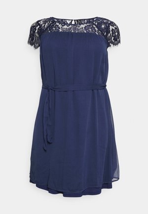 Robe bleu marine sans manches avec détail en dentelle sur les épaules, encolure ronde et ceinture en tissu nouée à la taille.