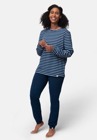 Maglietta a righe navy e bianca con maniche lunghe e scollatura rotonda, abbinata a pantaloni navy solidi. Entrambi realizzati in tessuto morbido e traspirante.