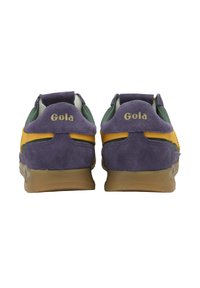 Par de zapatillas de ante morado con rayas amarillas, interior verde y suelas de goma, vistas desde la parte trasera que muestran la marca "Gola" en los talones.