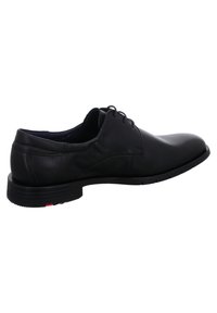 Schwarze Lederschuhe mit runder Zehenform, glatter Oberfläche, minimaler Naht und Gummisohle mit leichtem Absatz und roten Akzenten.