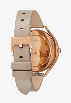 Swarovski-Uhr mit Gehäuse aus Roségold, beigem Lederarmband und minimalistischer Gestaltung. Verfügt über einen Verschluss mit Markenprägung und glatter Oberfläche.