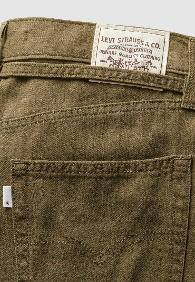 Pantalon vert olive en tissu texturé, avec une étiquette blanche Levi Strauss & Co. et des accents de poches arrière à double couture.