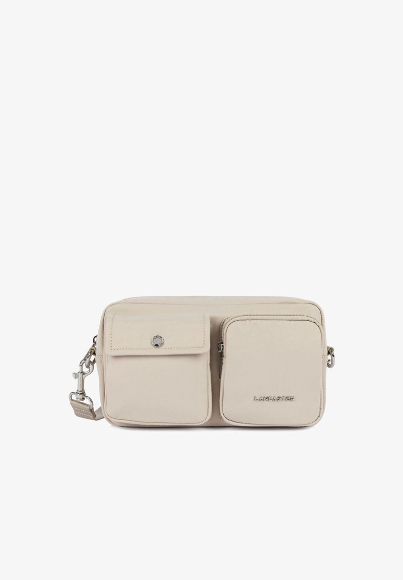 Sac bandoulière rectangulaire beige avec deux poches avant, l'une avec rabat et bouton, l'autre zippée avec logo « Lancaster ».