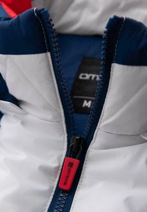 Puchowa kurtka o białym kolorze z granatowymi akcentami. Posiada zamek błyskawiczny z przodu z czerwonym uchwytem oraz metkę z nazwą marki.