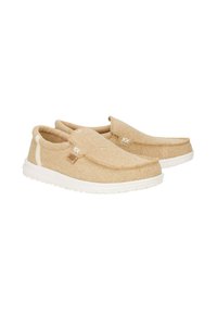 Zapatos beiges de tipo slip-on, hechos de un tejido texturizado con suela de goma blanca. Presentan una costura simple y un pequeño logo como acento en el lado.