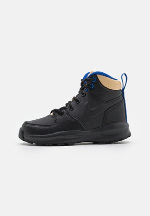 Black and tan mid-top sneaker with a textured leather upper, blue accents, lace-up closure, and a rubber sole. Features a pull tab at the heel.