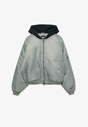 Šedá bomber bunda s černou kapucí, zipovým uzavíráním, manžetami s žebrováním a dvěma předními kapsami. Má hladkou, lesklou texturu a prošívané detaily.