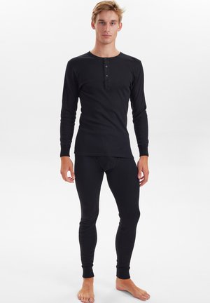 Sort langærmet termisk top med henley-udskæring og tre-knap lukning, parret med matchende tætsiddende sorte termiske leggings.