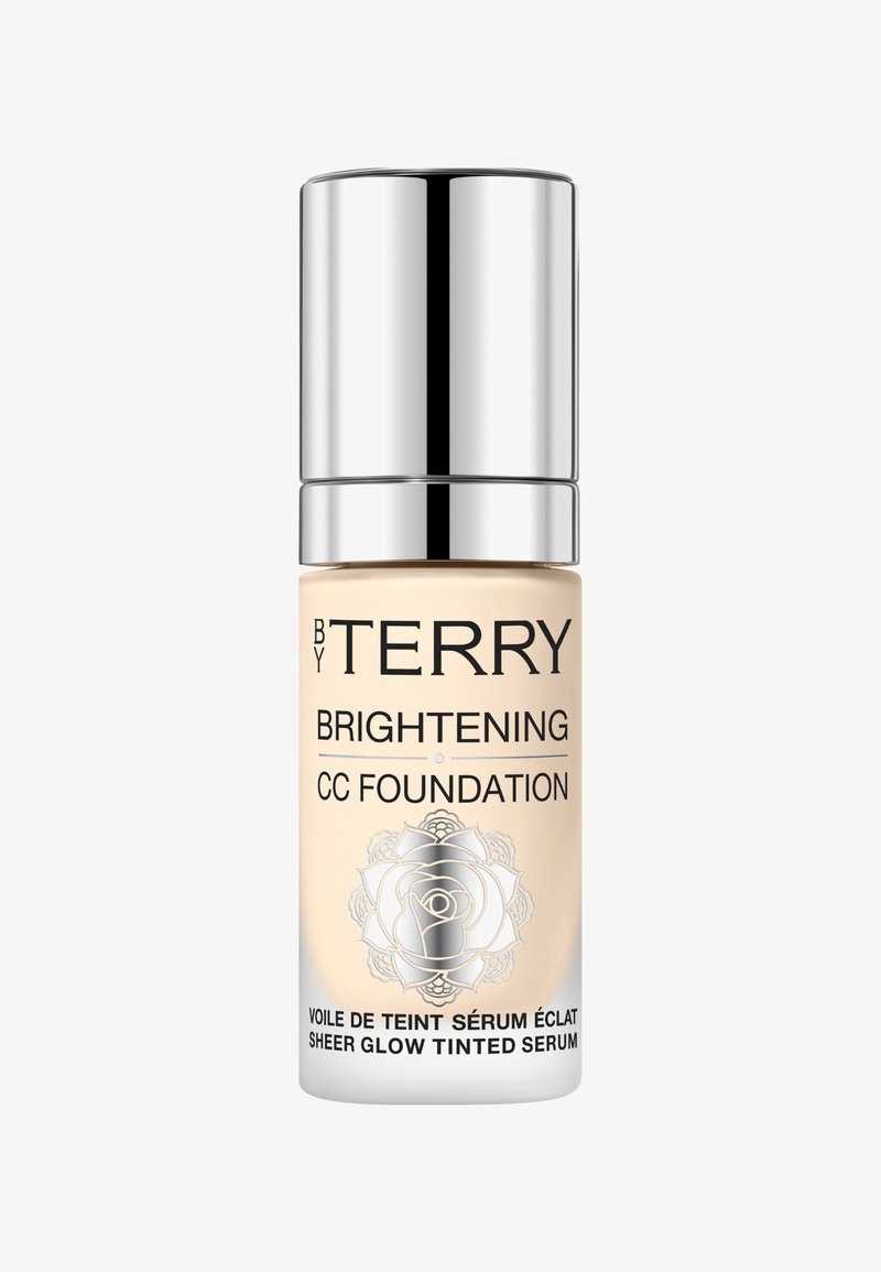 Flacon de fond de teint CC éclaircissant avec un capuchon argenté, liquide beige à l'intérieur et texte noir incluant le nom de la marque By Terry ainsi que le logo floral.