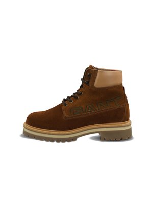 Brown suede boot with a tan leather ankle collar, black lace-up design, and embossed branding on the side. Thick, rugged sole.