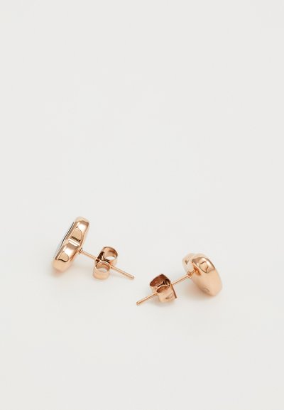 Boucles d'oreilles à clou en or rose avec une surface arrondie, présentant une finition polie et des fermoirs en métal. Design simple, adapté à un usage quotidien.