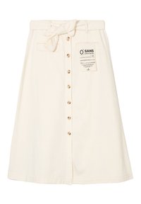 Kremvärinen, polvenpituinen puuvillahame, jossa on sidottava vyötärö, edessä nappisuljenta ja takana etikettitieto.