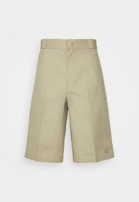 Shorts en coton beige avec une coupe décontractée, dotés d'un devant plat, de passants de ceinture et de poches latérales. Petite étiquette avec logo en bas à gauche.