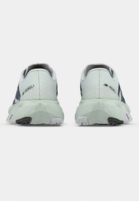 Light green and navy running shoes with a textured upper, angular sole, and prominent logos on the heel and side.