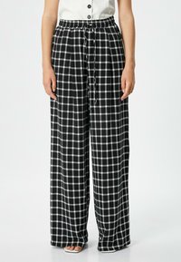 Pantalons à larges jambes en motif vichy noir et blanc, dotés d'une taille élastique et d'un cordon de serrage. Fabriqués en tissu léger avec une texture lisse.