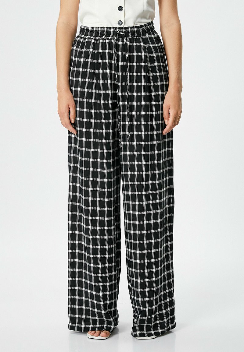 Pantalons à larges jambes en motif vichy noir et blanc, dotés d'une taille élastique et d'un cordon de serrage. Fabriqués en tissu léger avec une texture lisse.