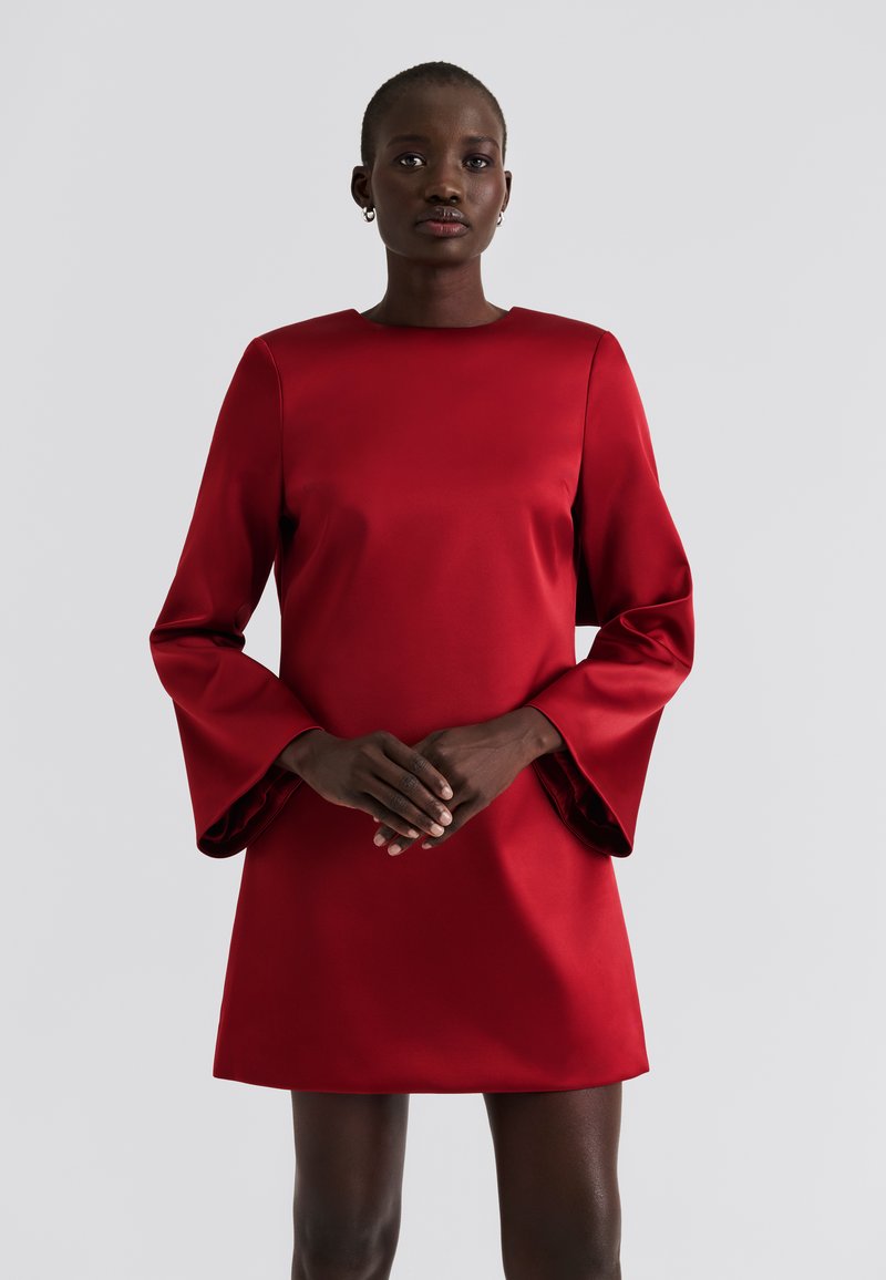 Red satin mini dress with a straight silhouette, round neckline, and flared cuffs. Smooth texture and minimalistic design.