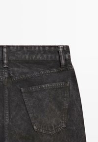 Jeans in denim nero con vita alta, una tasca posteriore e una finitura liscia. Il tessuto presenta un leggero effetto usurato.