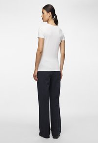 Valge lühikeste varrukatega T-särk, vormitud disain, koos tumesiniste triibuliste laia säärega pükstega. Sile tekstuur, lihtne kaelus ja minimalistlik stiil.