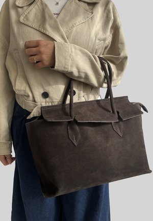 Borsa tote in suede marrone scuro con manici doppi, sopra a pattina e dettagli appuntiti. Design robusto con dettagli di cucitura visibili.